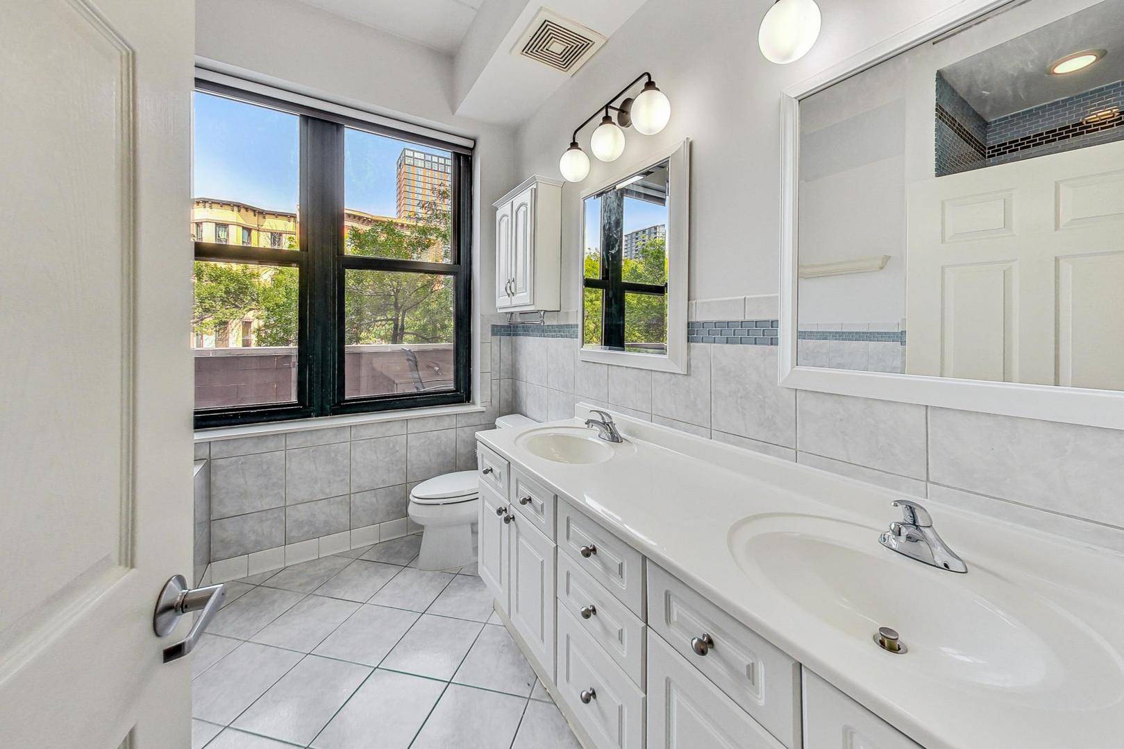 1301 West Washington Boulevard, Unit 208 Chicago, IL 60607 - Photo 18 of 37 a spacious bathroom with a double vanity sink a mirror and a bathtub