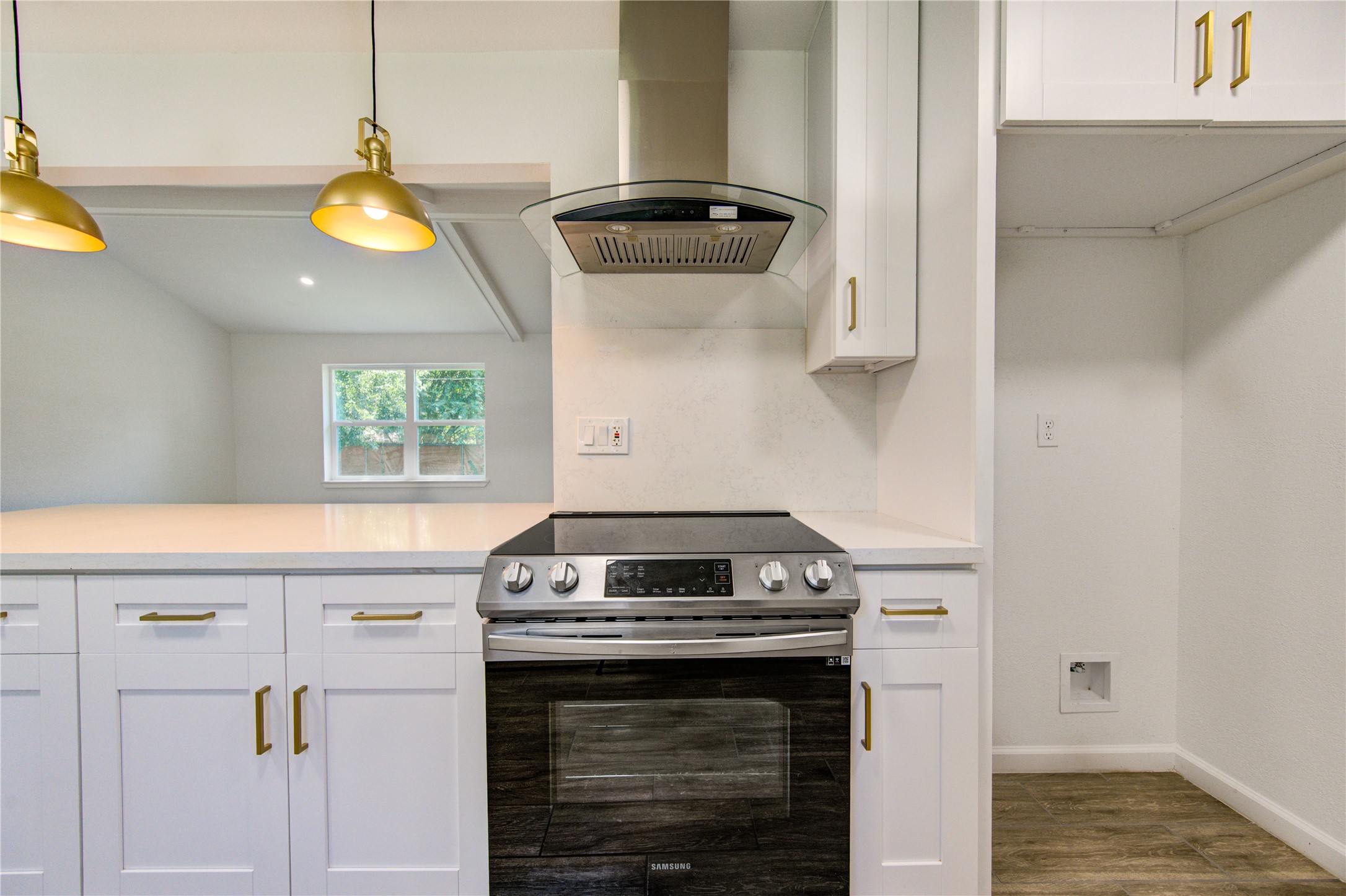 5411 Logston Lane Spring, TX 77389 - Photo 18 of 50 Sleek kitchen featuring a modern stainless steel range with overhead hood, complemented by white cabinetry with gold hardware and elegant pendant lighting.