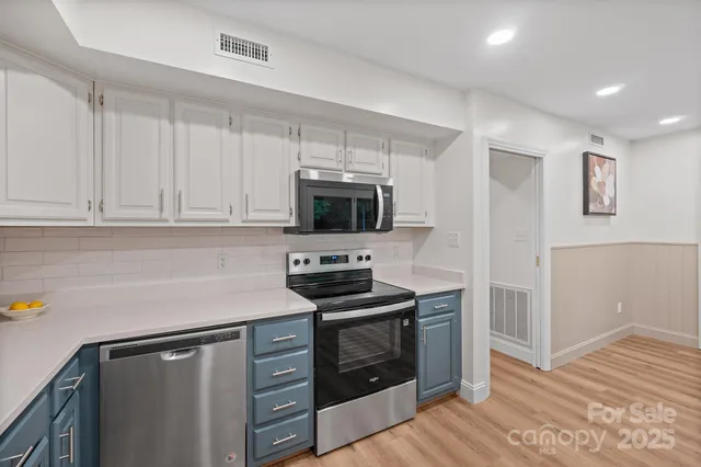 a kitchen with white cabinets and stainless steel appliances