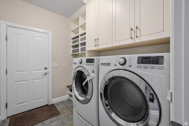 1456 Firelight Way Sandy, UT 84092 - Photo 19 of 22 Laundry room featuring washing machine and dryer, a textured ceiling, cabinet space, and light stone finish floors