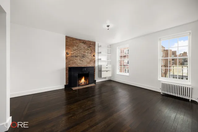 an empty room with wooden floor a fireplace and windows