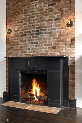 a view of an empty room with wooden floor fireplace and a window
