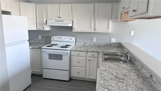 a kitchen with granite countertop white cabinets and white appliances