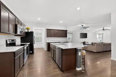 a large kitchen with stainless steel appliances lots of counter space and wooden floor