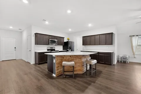 a large kitchen with cabinets wooden floor and stainless steel appliances