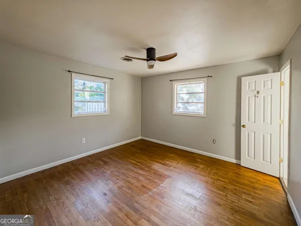 a view of an empty room with wooden floor and a window