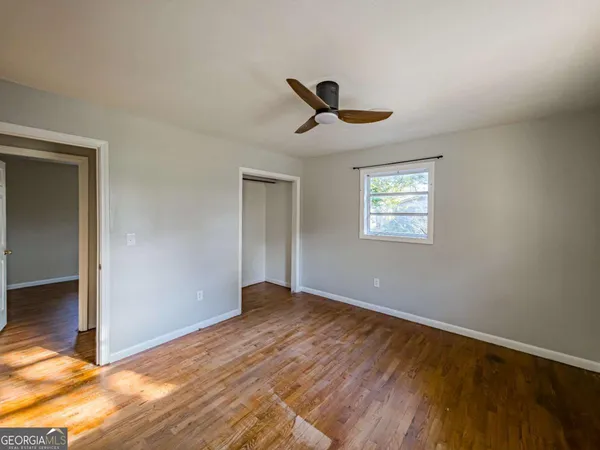 a view of empty room with wooden floor and fan