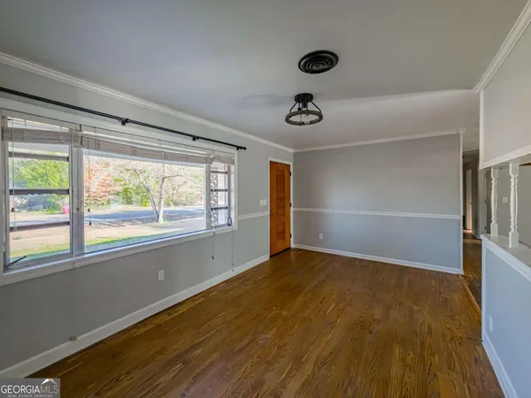 a view of an empty room with a window and wooden floor