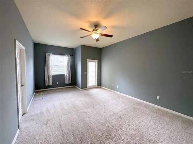 an empty room with fan and windows