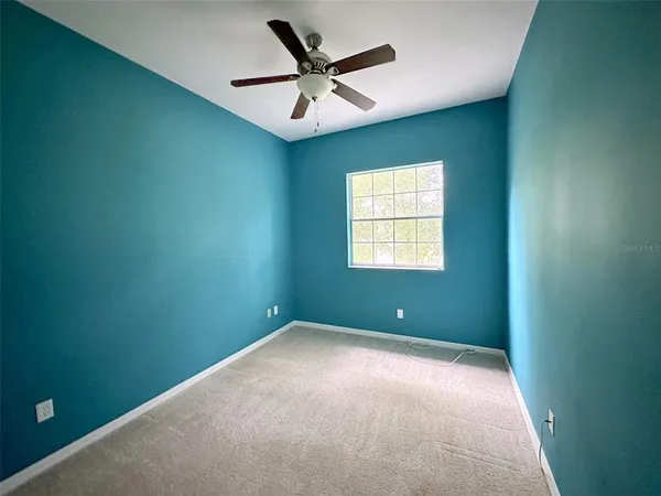 an empty room with windows and fan