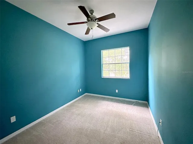 an empty room with windows and fan