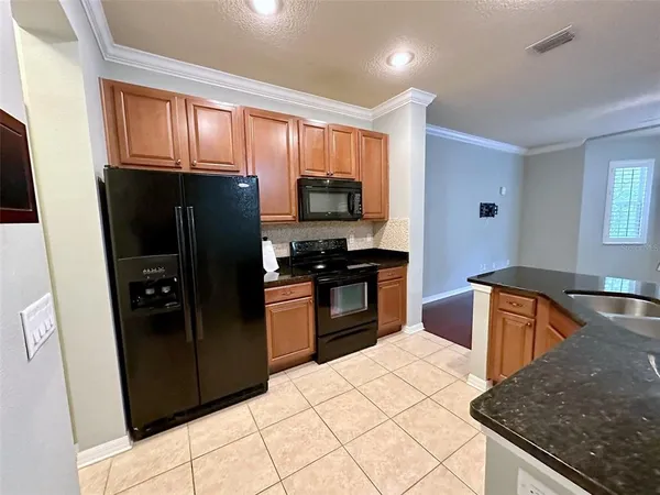 a kitchen with granite countertop a refrigerator and a stove top oven