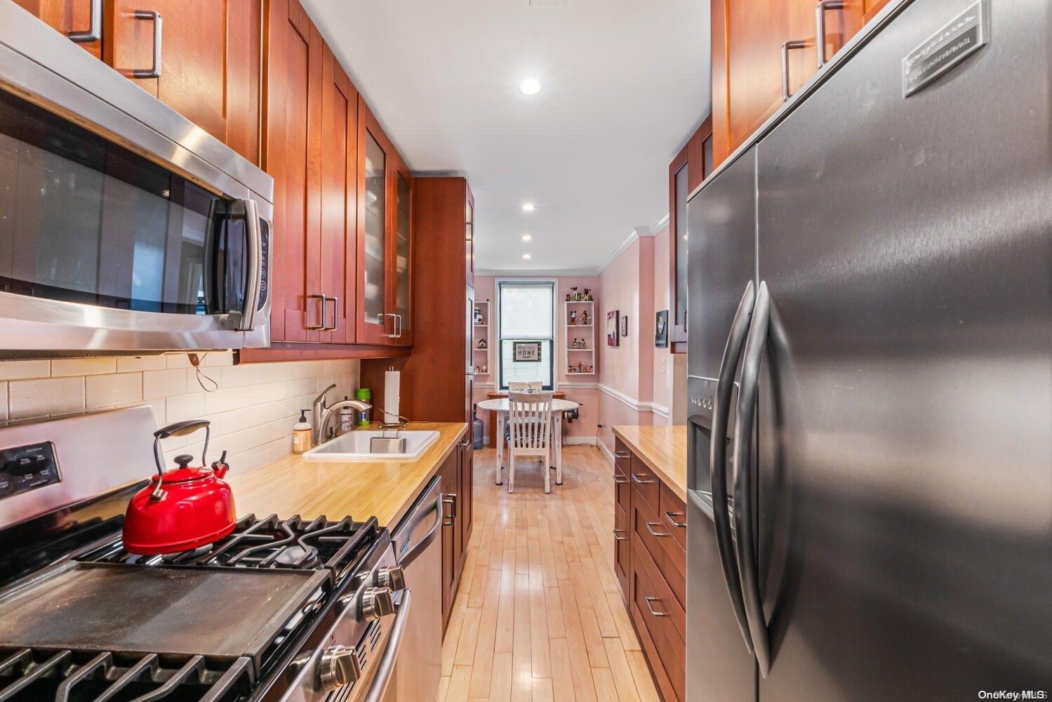 84-19 51st Avenue, Unit 1P Queens, NY 11373 - Photo 8 of 18 a kitchen with stainless steel appliances granite countertop a refrigerator a stove and a sink with wooden floor
