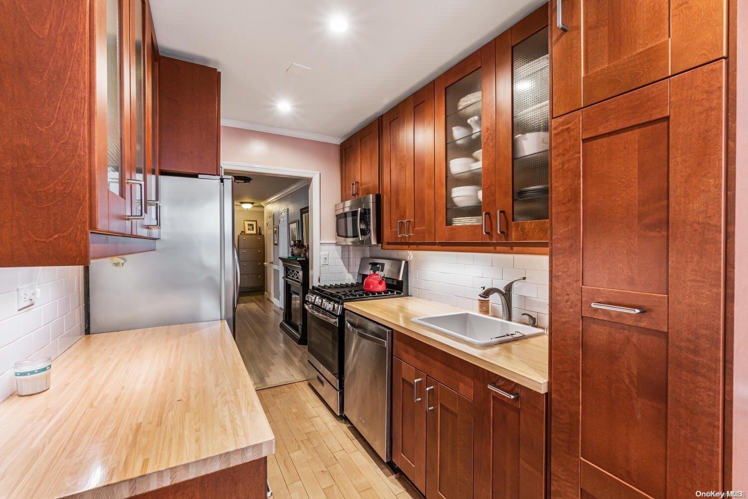 84-19 51st Avenue, Unit 1P Queens, NY 11373 - Photo 9 of 18 a kitchen with a sink refrigerator and cabinets