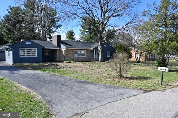 a front view of a house with a garden and trees