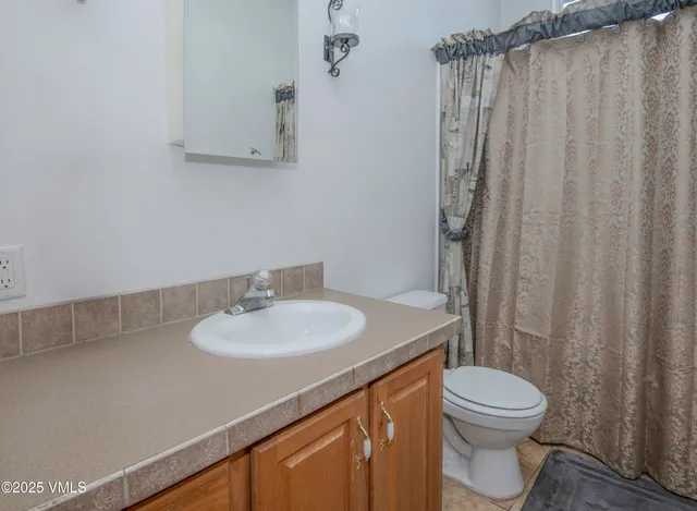 a bathroom with a sink a toilet and shower curtain