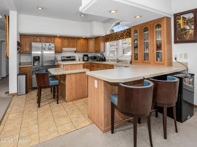 a kitchen with stainless steel appliances granite countertop a table chairs and a refrigerator