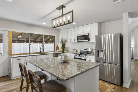 a kitchen with stainless steel appliances granite countertop a kitchen island a stove a table and chairs in it