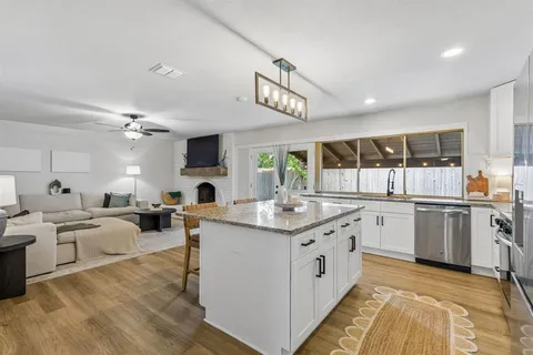 a large kitchen with stainless steel appliances kitchen island granite countertop a table chairs refrigerator and microwave