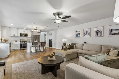 a large white kitchen with a stove a sink dishwasher and a refrigerator with wooden floor