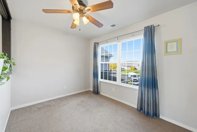 an empty room with windows and chandelier fan
