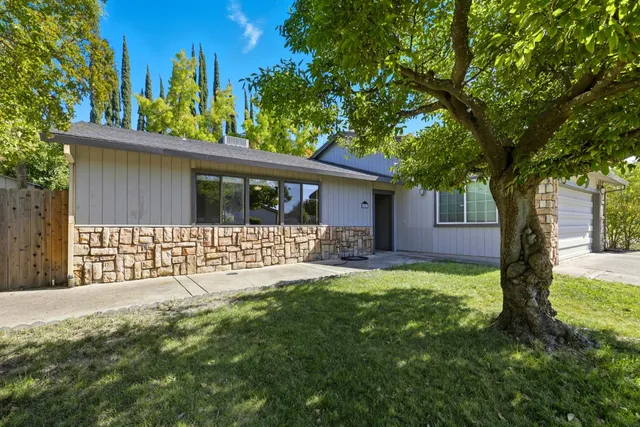 a front view of a house with a garden and trees
