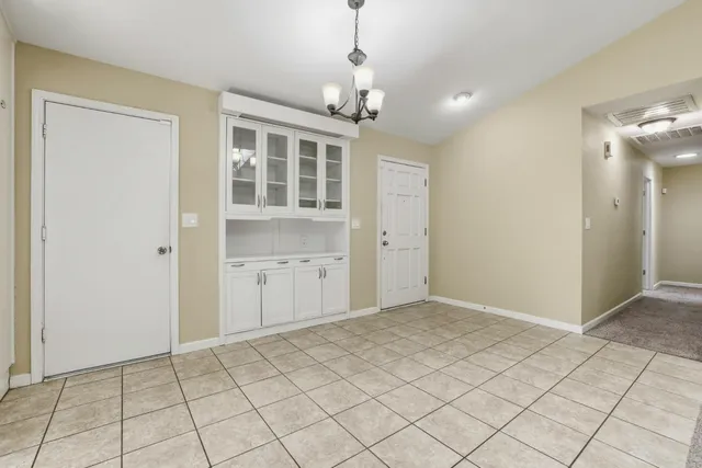 a view of an empty room with window and chandelier