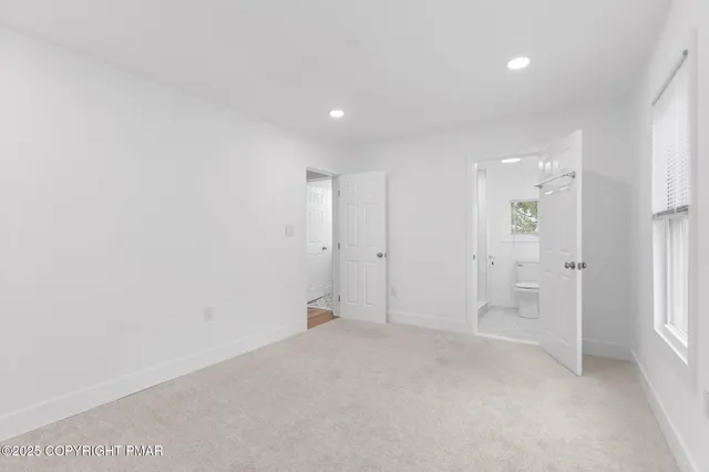 an empty room with white cabinet and windows