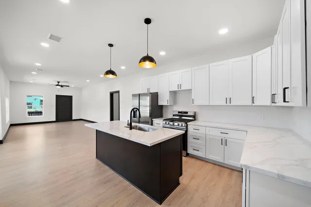 a kitchen with kitchen island granite countertop a sink appliances and cabinets