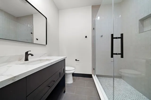 a bathroom with a sink a toilet and shower