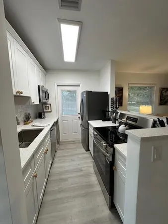 a kitchen with stainless steel appliances a stove top oven a sink dishwasher a refrigerator and a microwave