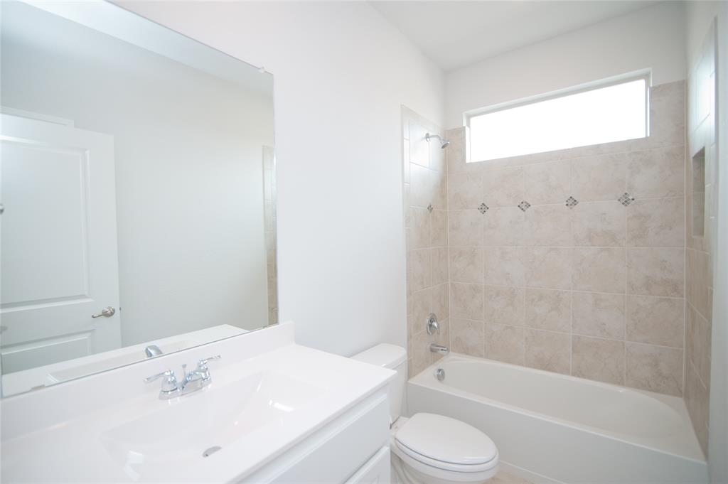 1021 Gillespie Drive Fort Worth, TX 76247 - Photo 25 of 38 a bathroom with a bathtub shower sink vanity and toilet