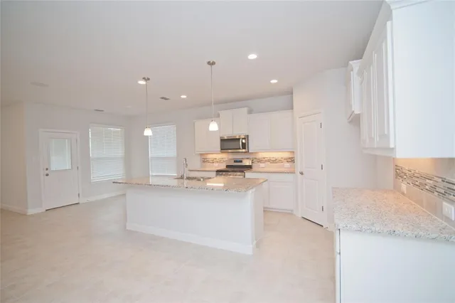 a kitchen with kitchen island sink stove and cabinets