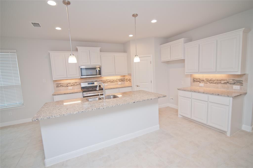 1021 Gillespie Drive Fort Worth, TX 76247 - Photo 7 of 38 a kitchen with kitchen island sink stove and cabinets