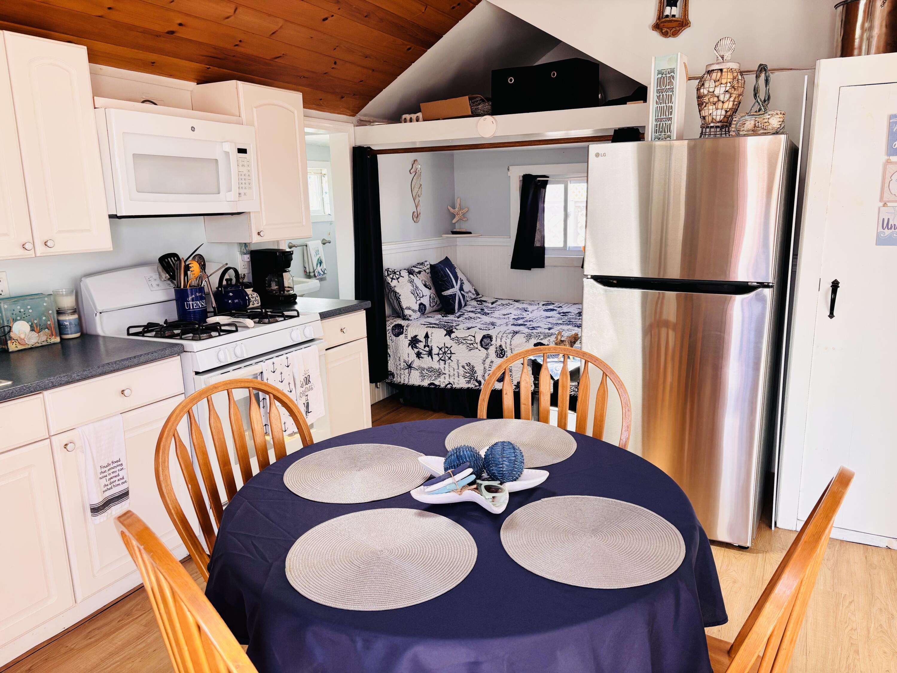 241 Old Wharf Road, Unit 91 Dennis Port, MA 02639 - Photo 5 of 16 a dining room with furniture a kitchen view and a chandelier