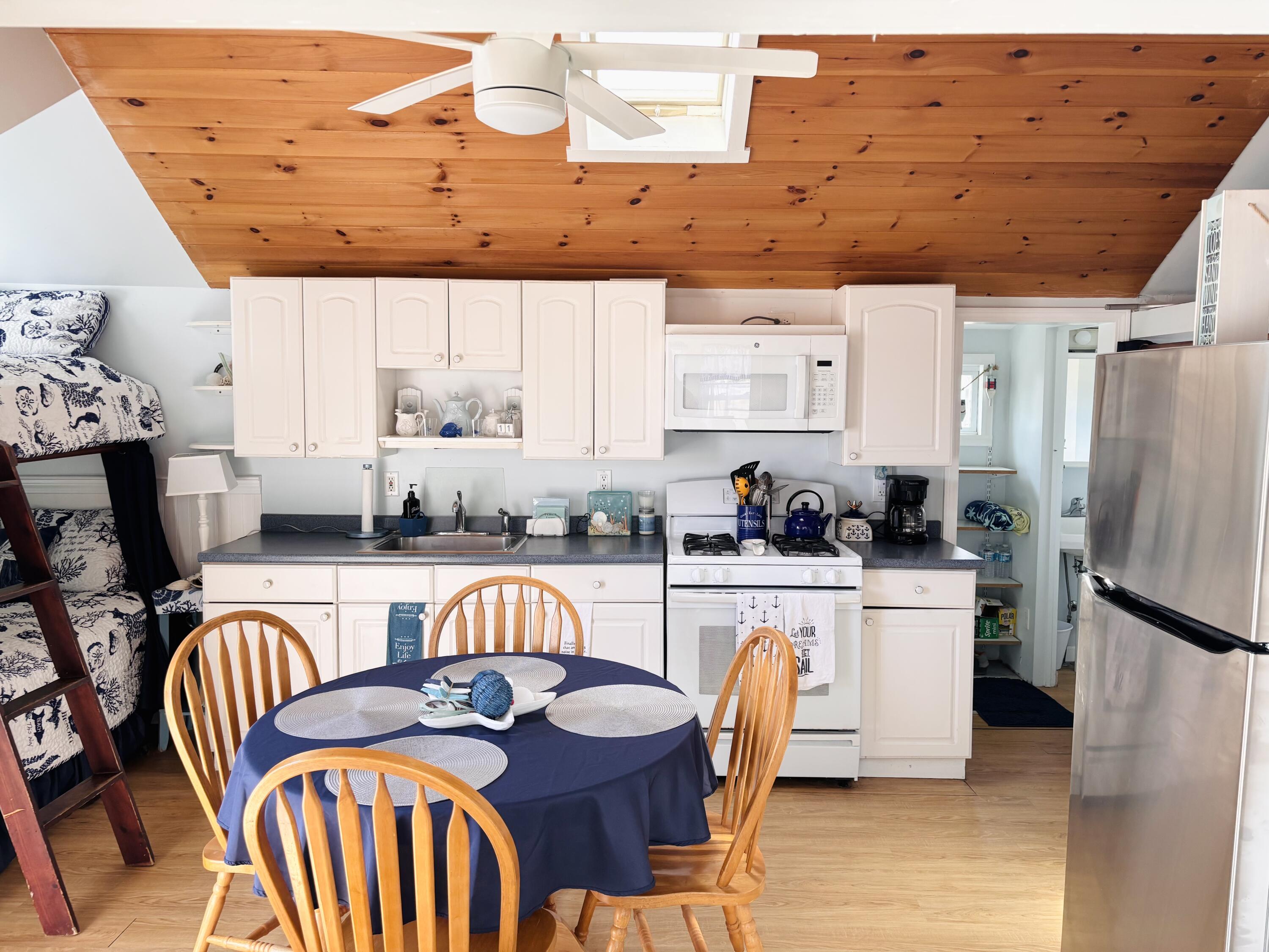 241 Old Wharf Road, Unit 91 Dennis Port, MA 02639 - Photo 6 of 16 a kitchen with stainless steel appliances granite countertop a dining table chairs and a refrigerator