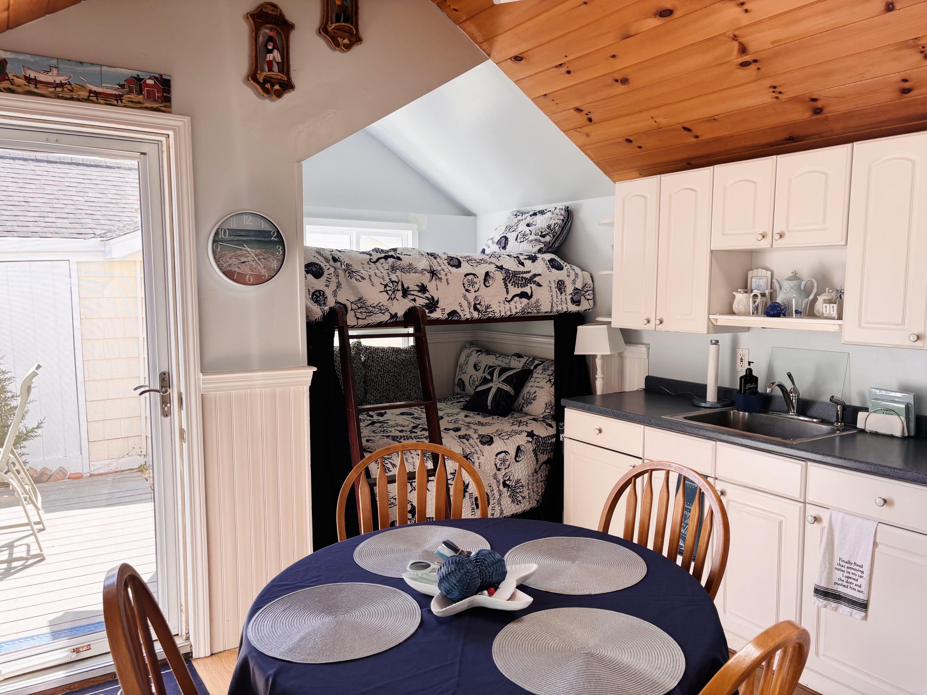 241 Old Wharf Road, Unit 91 Dennis Port, MA 02639 - Photo 7 of 16 a kitchen with granite countertop a dining table chairs stainless steel appliances and wooden floor