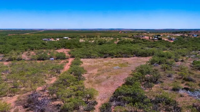an aerial view of residential houses with outdoor space and trees