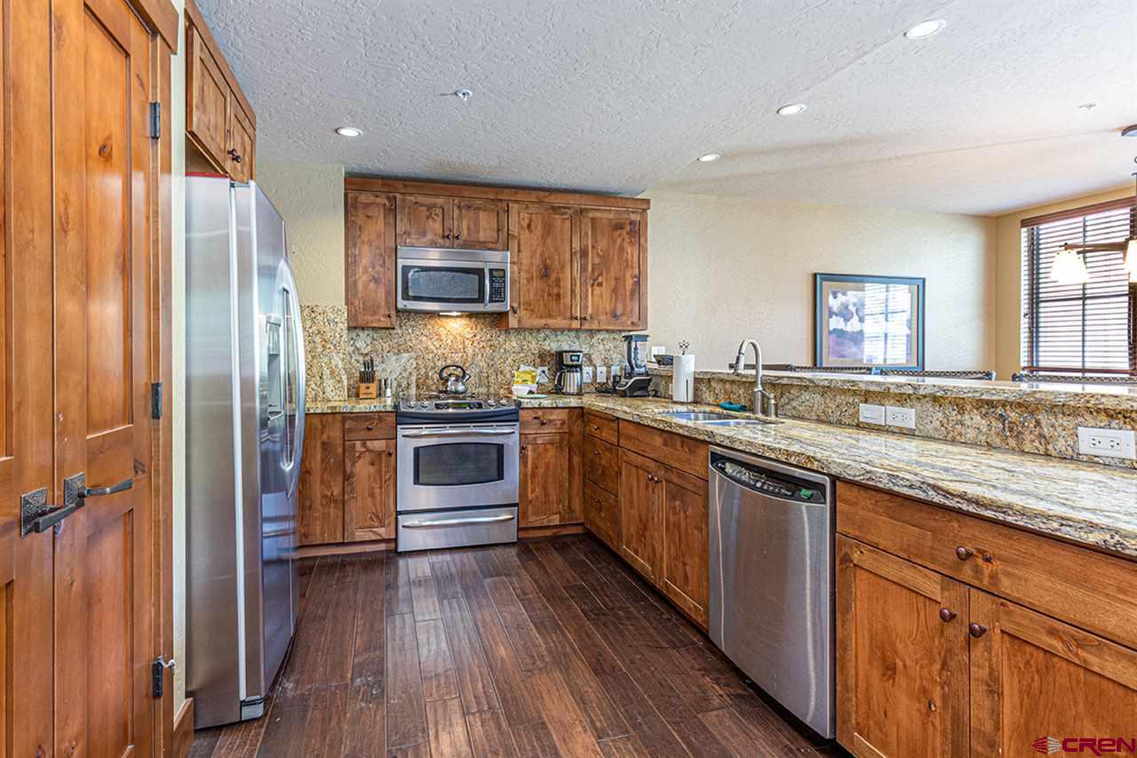 24 Sheol Street, Unit 504 Durango, CO 81301 - Photo 15 of 30 a kitchen with stainless steel appliances granite countertop a refrigerator a sink dishwasher a stove and white countertops with wooden floor