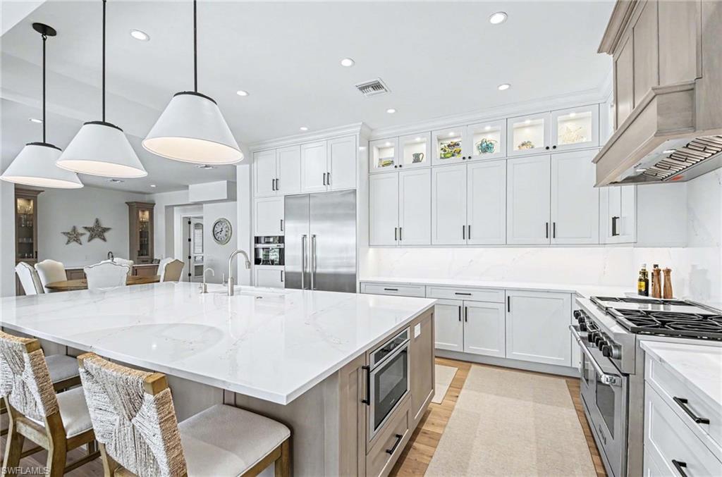 1888 6th Street South Naples, FL 34102 - Photo 8 of 37 a kitchen with stainless steel appliances granite countertop a sink a stove a refrigerator and island with wooden floor