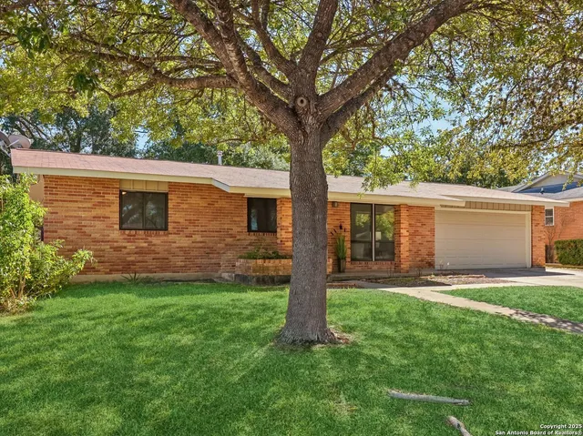 a front view of a house with a yard and trees