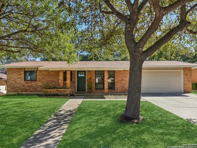 a front view of a house with a yard and trees