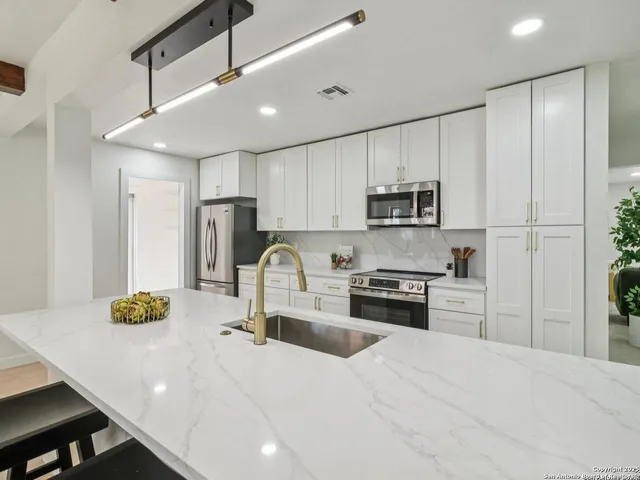 a large kitchen with stainless steel appliances granite countertop a sink and dishwasher a stove top oven with wooden floor