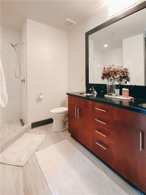 747 Ralph McGill Boulevard Northeast, Unit 217 Atlanta, GA 30312 - Photo 13 of 28 a bathroom with a granite countertop sink a toilet and a mirror