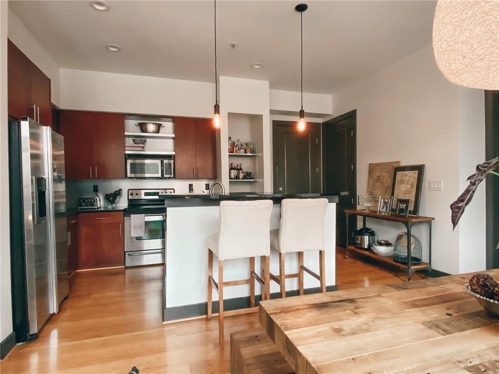 747 Ralph McGill Boulevard Northeast, Unit 217 Atlanta, GA 30312 - Photo 3 of 28 a kitchen with stainless steel appliances kitchen island granite countertop a refrigerator a stove a sink and a dining table with wooden floor