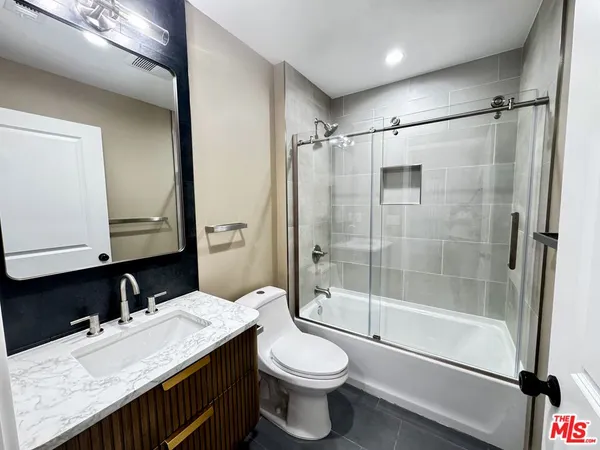 a bathroom with a granite countertop sink toilet and shower