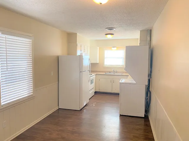 a kitchen with a refrigerator a sink and wooden floor