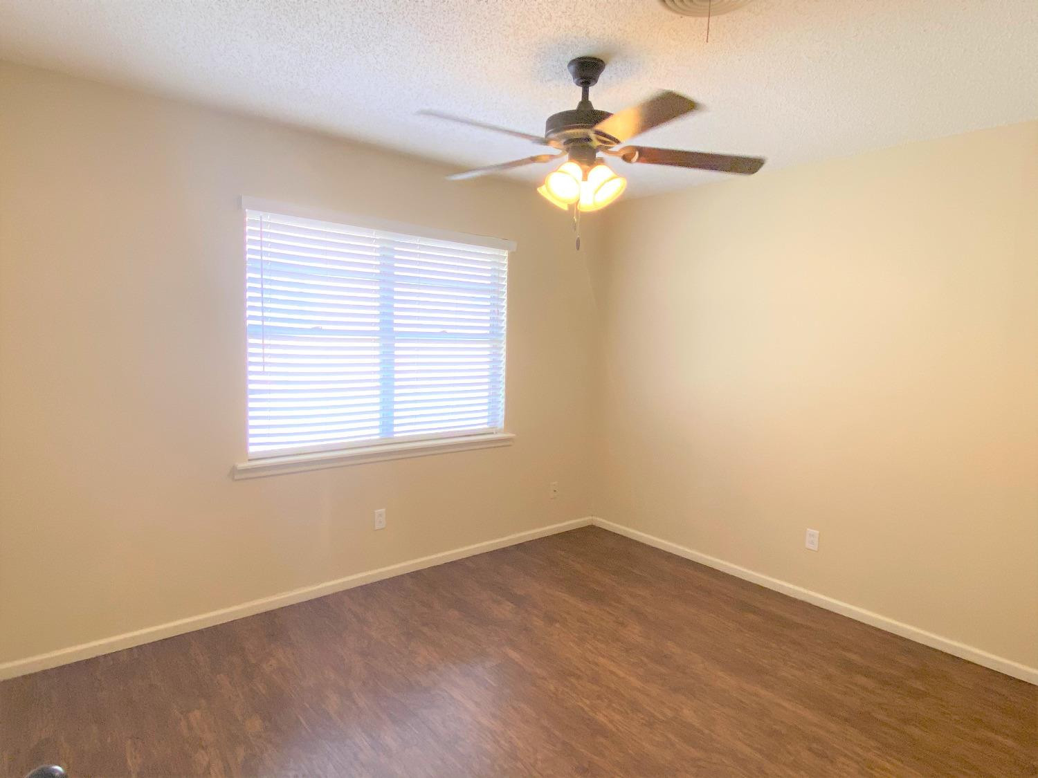 4210 18th Street, Unit A Lubbock, TX 79416 - Photo 6 of 12 an empty room with wooden floor fan and windows