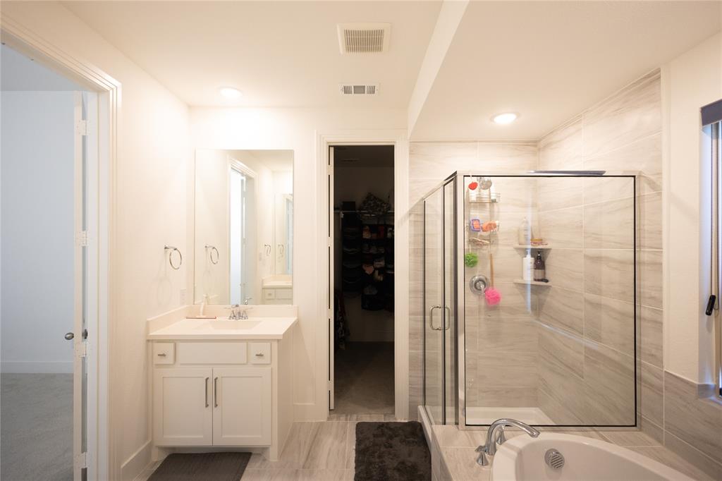 3017 Andorra Road McKinney, TX 75071 - Photo 22 of 40 White vanity with a single sink, walk-in shower with glass enclosure, white soaking tub, and tiled flooring