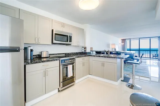 a kitchen with granite countertop a sink appliances cabinets and a counter top space